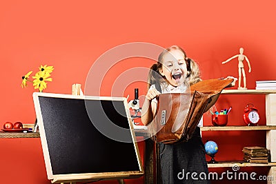 Schoolgirl with happy face and ponytails holds open schoolbag Stock Photo