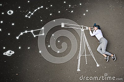 Schoolgirl laying on a asphalt, watching stars through a chalk-drawn telescope Stock Photo