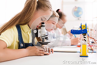 Schoolgirl looking at microscope at stem robotic class Stock Photo