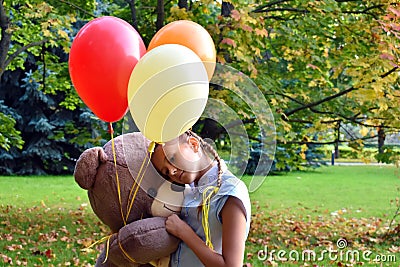girl with big teddy bear and balloons in the park. Problems teenagers at school Stock Photo