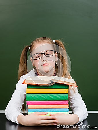 Schoolgirl with pile books near empty green chalkboard Stock Photo