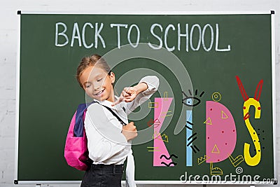 Schoolgirl with finger at backpack near Stock Photo