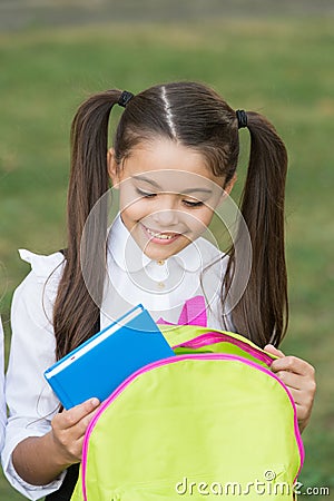 Schoolgirl putting book inside backpack, ready for lessons concept Stock Photo