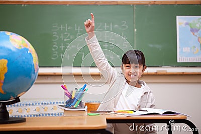 Schoolgirl raising her hand to answer a question Stock Photo