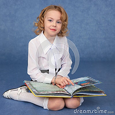Schoolgirl reading book sitting on floor Stock Photo