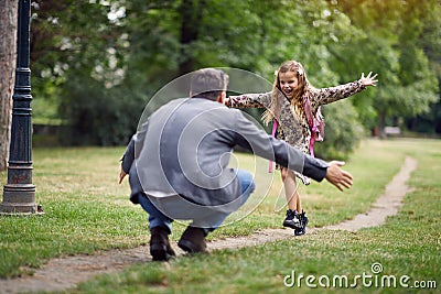 Schoolgirl running to dad to give him a hug Stock Photo