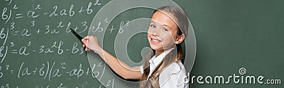 schoolgirl smiling at camera while pointing Stock Photo
