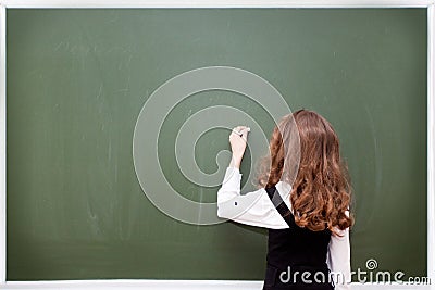 Schoolgirl writes on a blackboard Stock Photo