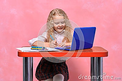 Schoolgirl writes lessons in notebook. online learning for laptop Stock Photo