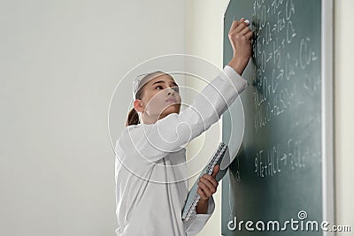 Schoolgirl writing chemistry formula on blackboard Stock Photo