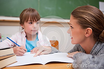 Schoolgirl writing a while her teacher is talking Stock Photo
