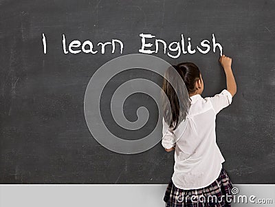 Schoolgirl writing I learn English with chalk on blackboard school Stock Photo