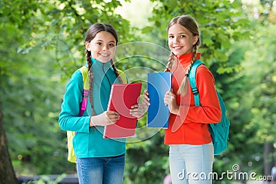 Schoolgirls with backpacks and textbooks in forest, exploring nature concept Stock Photo