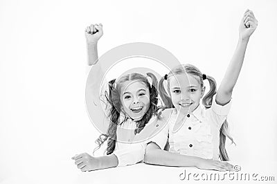 Schoolgirls happy keep hands up while sit at desk white background. Win school quiz. They know right answer. Schoolgirls Stock Photo