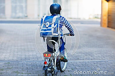 Schoolkid boy in safety helmet riding with bike in the city with backpack. Happy child in colorful clothes biking on Stock Photo