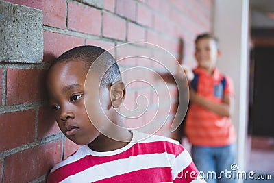 Schoolkid bullying a sad boy in corridor Stock Photo