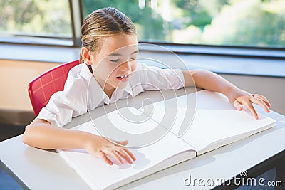 Schoolkid reading braille book in classroom Stock Photo