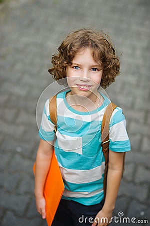 The schoolkid stand on a schoolyard and smiles. Stock Photo