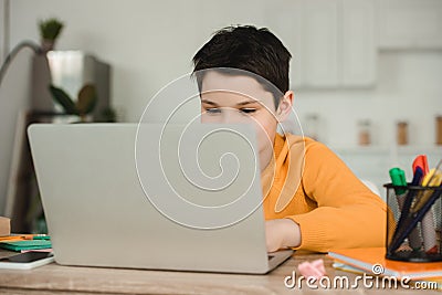 Schoolkid using laptop while doing schoolwork at home Stock Photo