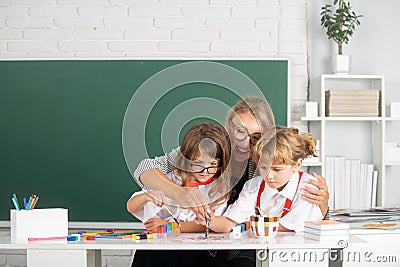 Schoolkids with teacher. Happy children from elementary school study at draw lesson. Pupils girl and boy with teacher Stock Photo
