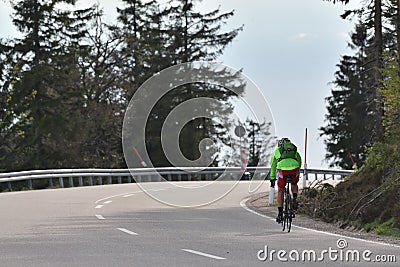 Schwarzwald, Germany - April 25 2019: Highway through the forest and a cyclist in a green jacket with a backpack and Editorial Stock Photo