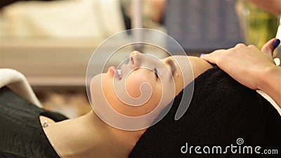 Schöne junge Frau, die Gesichtsmassage mit geschlossenen Augen in einem Badekurortsalon empfängt stock video Schöne junge Frau, die Gesichtsmassage mit geschlossenen Augen in einem Badekurortsalon empfängt stock video