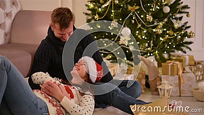 Schöne junge Paare in der Liebe, die Santa Hats, liegend auf dem Boden nahe bei einem Kamin und Nizza verziert trägt stock footage Schöne junge Paare in der Liebe, die Santa Hats, liegend auf dem Boden nahe bei einem Kamin und Nizza verziert trägt stock footage