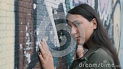 Schönes Hippie-Mädchen, das nahe der Wand mit Graffiti aufwirft H?nde auf der Wand stock video Schönes Hippie-Mädchen, das nahe der Wand mit Graffiti aufwirft H?nde auf der Wand stock video