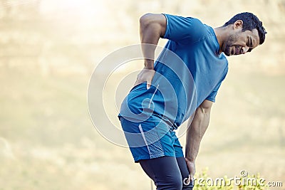 This sciatic nerve is such a problem. a handsome young man standing alone and suffering from backache during his outdoor Stock Photo