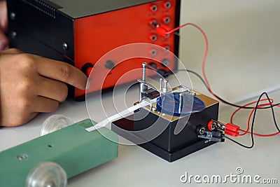 Science classroom, students are conducting a physics experiment on the speed of objects using a ticker timer device. Stock Photo