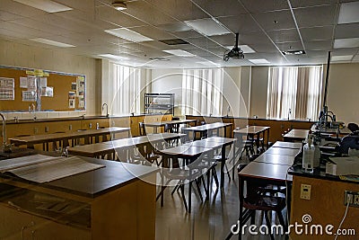 Science laboratory classroom - wooden lab tables with black countertops and sinks - windows with closed blinds - bulletin board Editorial Stock Photo