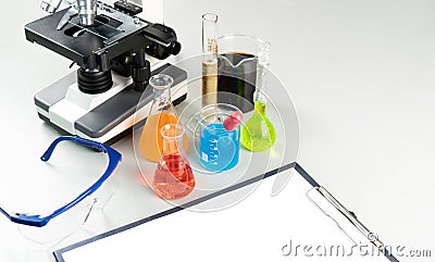 Science lecture clipboard with chemical experiment in school laboratory with beakers, microscope for testing. Stock Photo