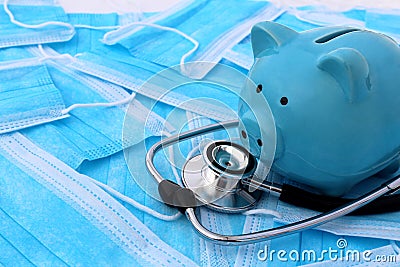 On medical masks lies a stethoscope and a piggy bank. Stock Photo