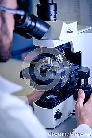 Scientific handling a light microscope examines a laboratory sample for pharmaceutical bioscience research. Concept of science, Stock Photo