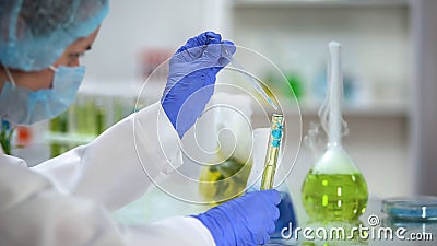 Scientist adding blue liquid in tube with yellow oily substance, biofuel testing Stock Photo