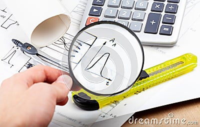 Scientist, architect or electrician holding a magnifying glass and inspecting analyzing data on a graph, chart, engineering Stock Photo