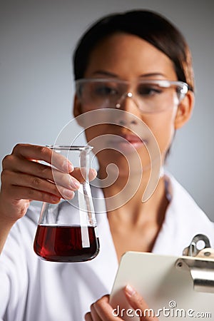 Scientist Examining Liquid In Flask Holding Clipboard Stock Photo