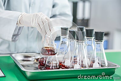 Scientist are experimenting with red chemicals, laboratory assistant prepare instrument for chemical lab experiment in Lab Stock Photo