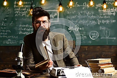 Scientist in glasses type on vintage typewriter. Scientist with beard typewrite research paper with microscope and books Stock Photo