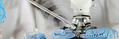 Scientist in gloves conducts laboratory studies of liquid on microscope Stock Photo