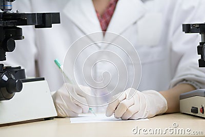 Scientist hold slide in left hand and write something down Stock Photo