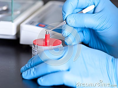 Scientist holds standard weight with tweezers Stock Photo