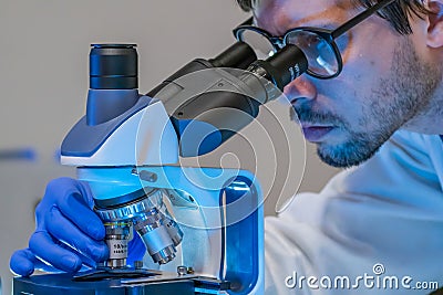 Scientist in laboratory is looking inside microscope. Microbiology and research concept. Stock Photo