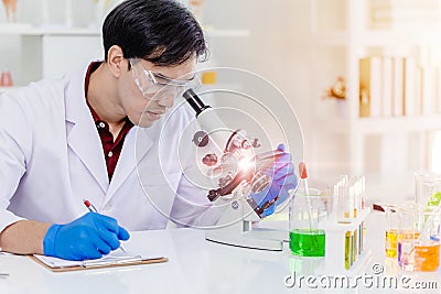 Scientist looking at microscope or Doctor pay attention working in lab and taking note or writing list of virus definition in Stock Photo