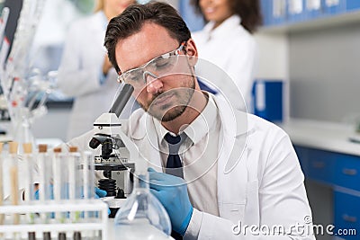 Scientist Looking Through Microscope In Laboratory, Male Researcher Doing Research Experiments Stock Photo