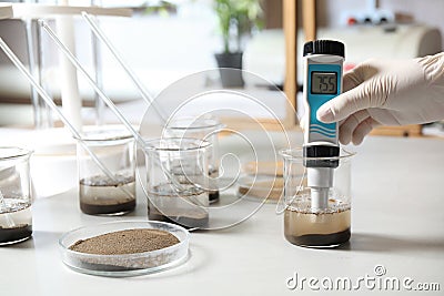 Scientist measuring acidity and pH of soil at table. Laboratory analysis Stock Photo