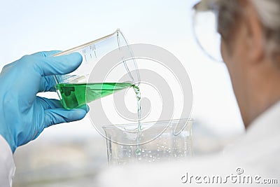 Scientist Pouring Green Liquid Into Beaker Stock Photo