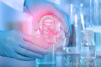 Scientist pouring liquid into beaker at table. Laboratory analysis Stock Photo