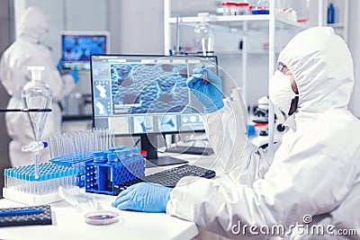 Scientist in protection suit holding sample of infected blood with coronavirus Stock Photo