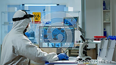 Scientist in protection suit typing on pc working in medical laboratory Stock Photo